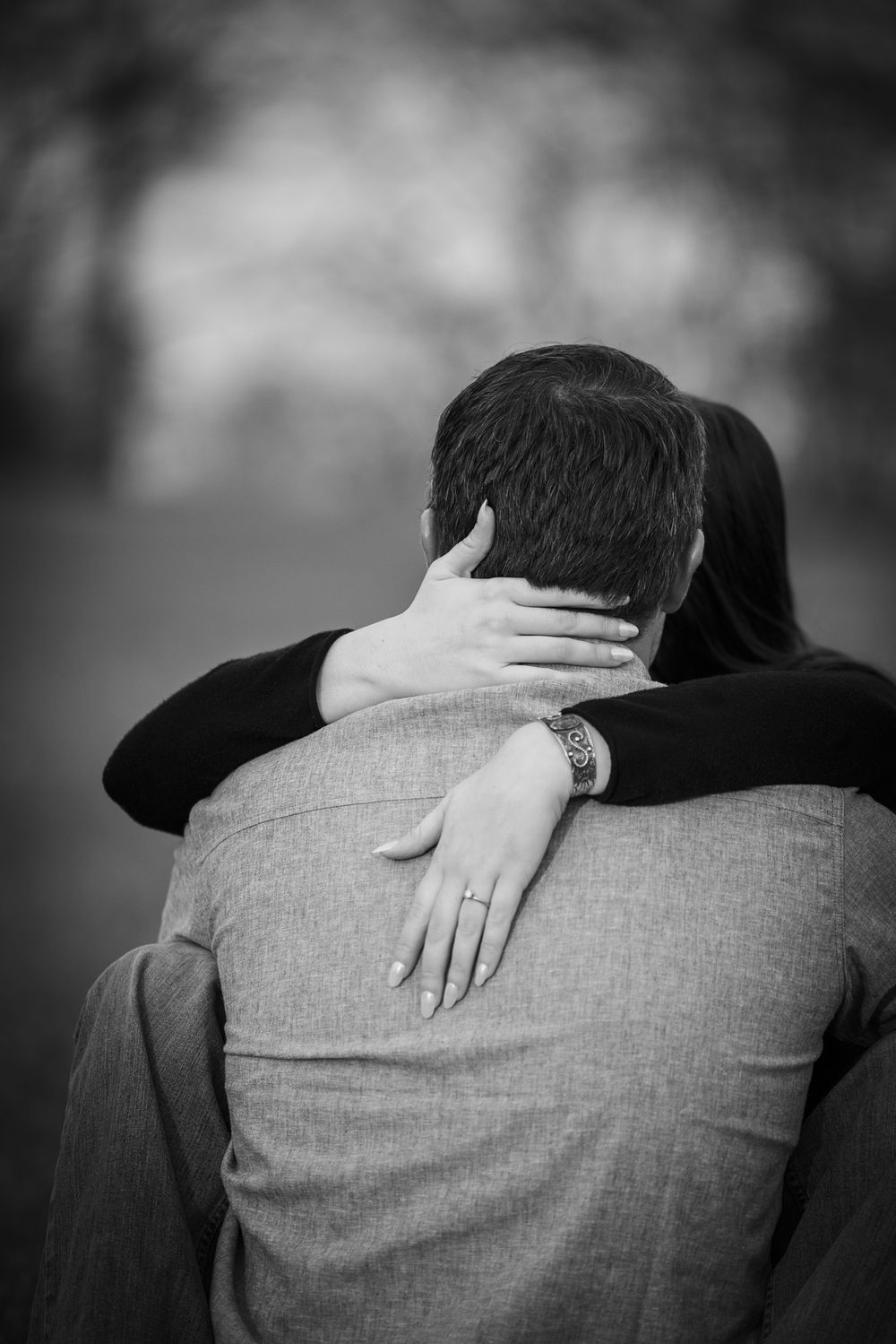 An intimate black and white portrait of a couple embracing, with focus on their hands and close connection.