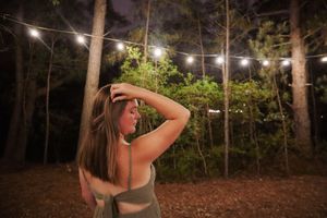 Figure silhouetted against string lights at night outdoors.