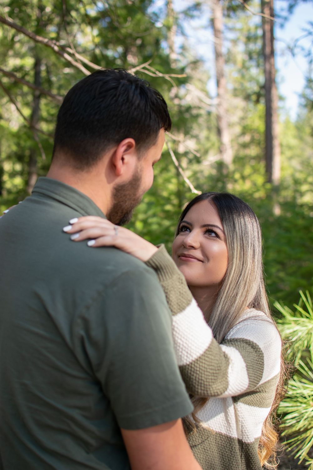 A romantic outdoor portrait of a couple embracing among green foliage.