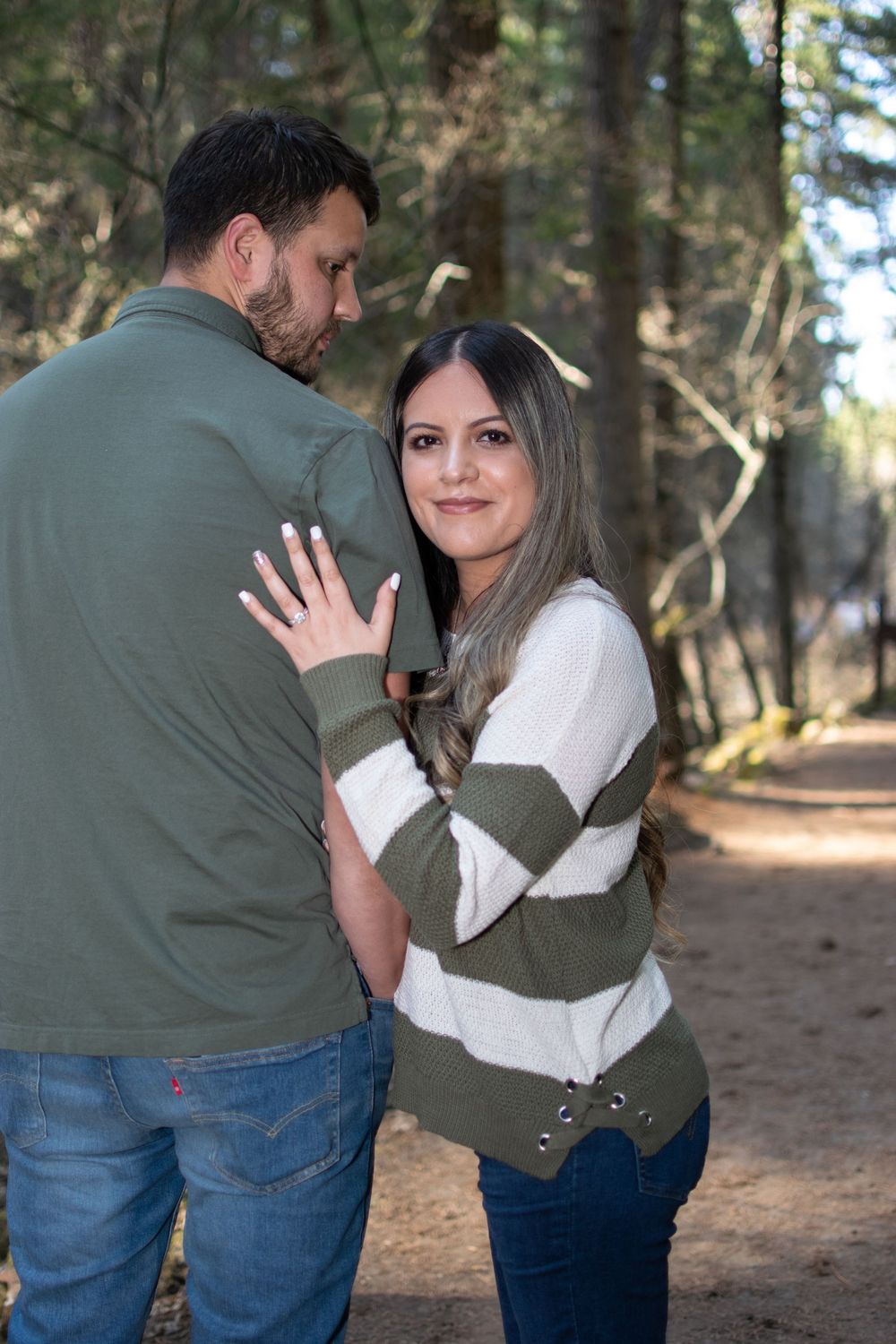 An intimate moment captured on a forest trail with pine trees in the background.