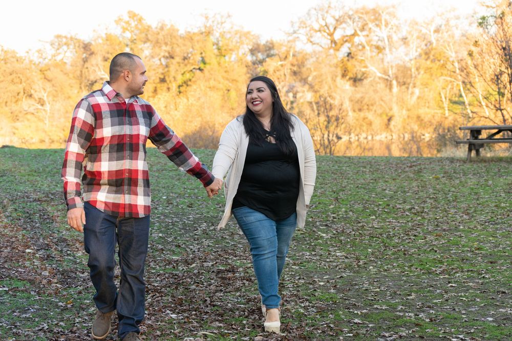 A couple walking together through an autumn field during golden hour.