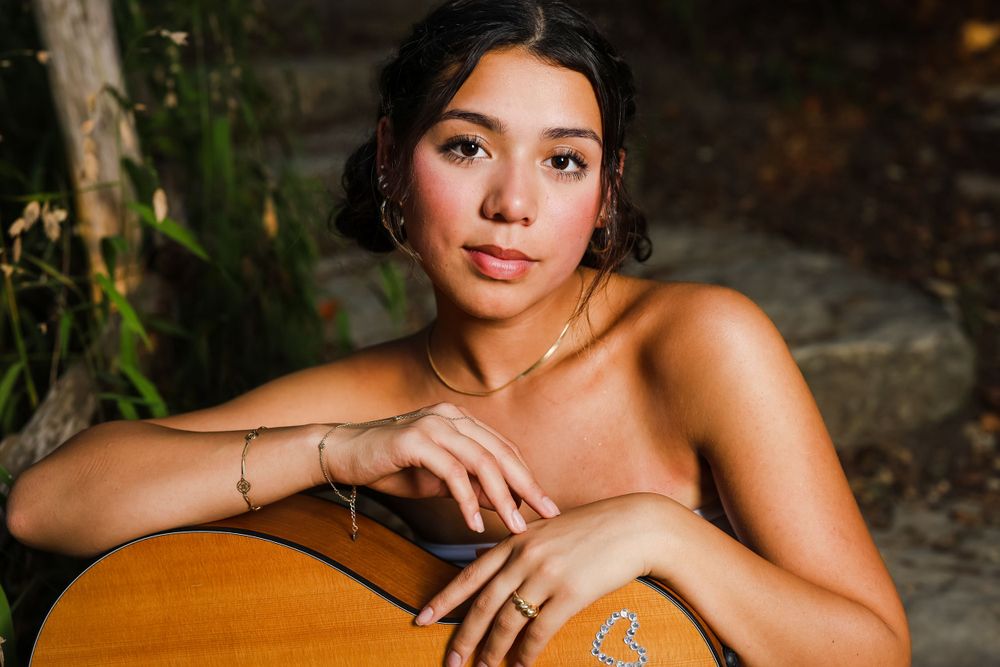 Elegant portrait with acoustic guitar in natural lighting.
