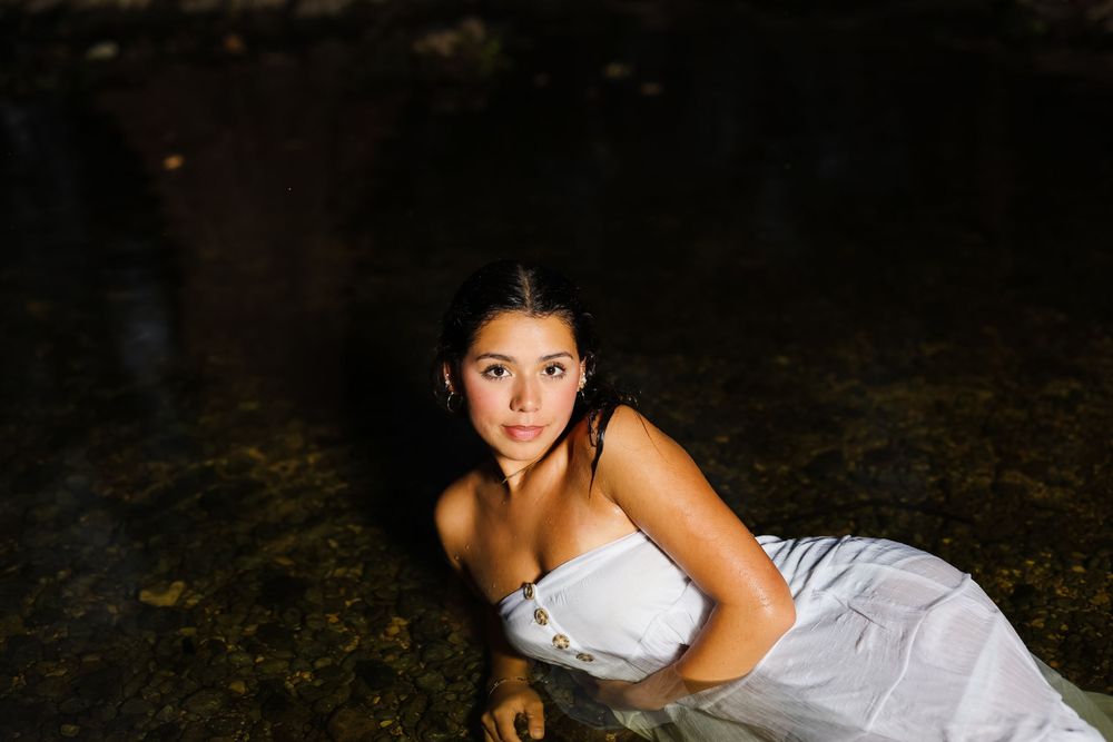 Low light portrait by water in white dress.