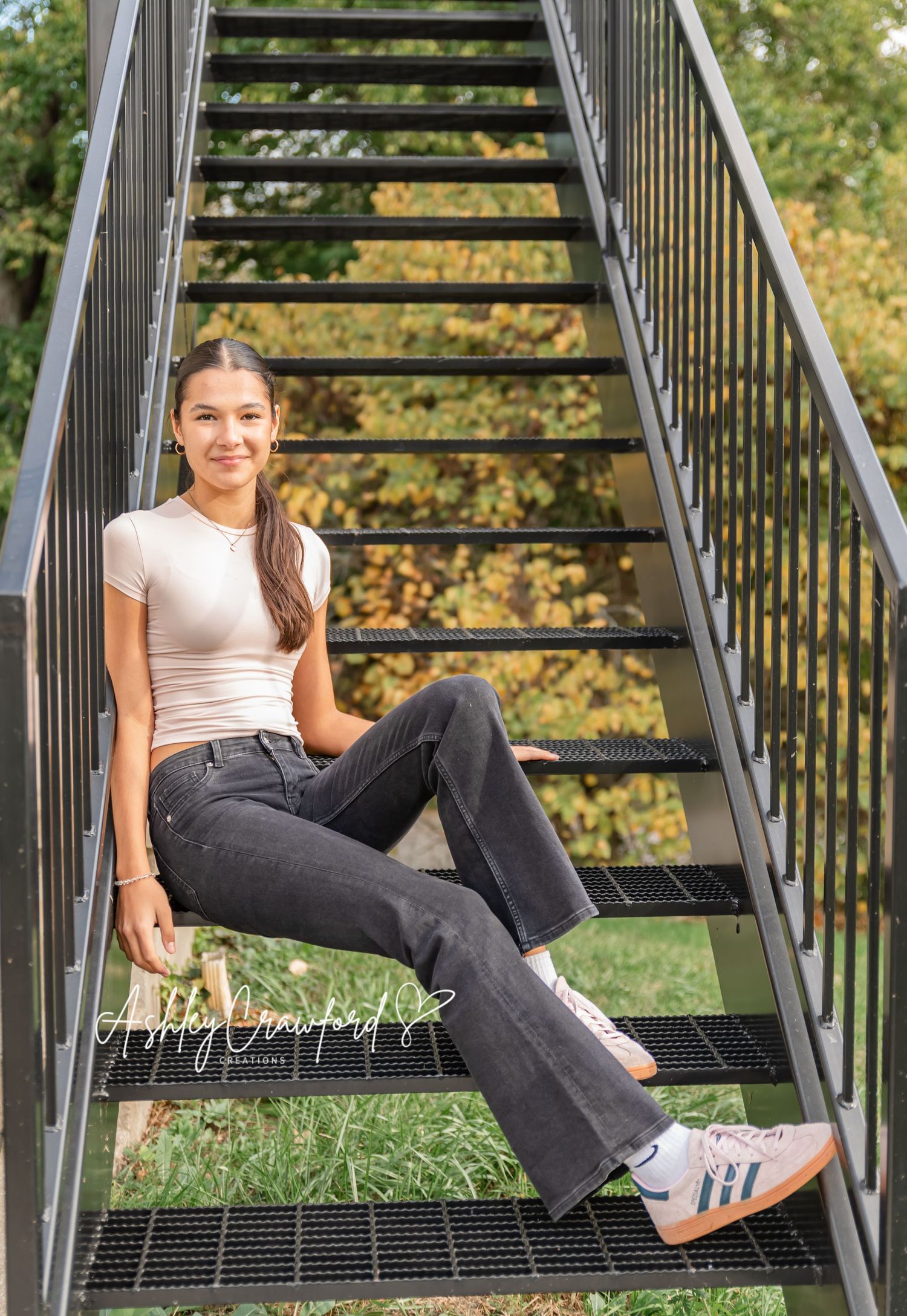 Someone sits casually on metal stairs wearing jeans and a cream top.