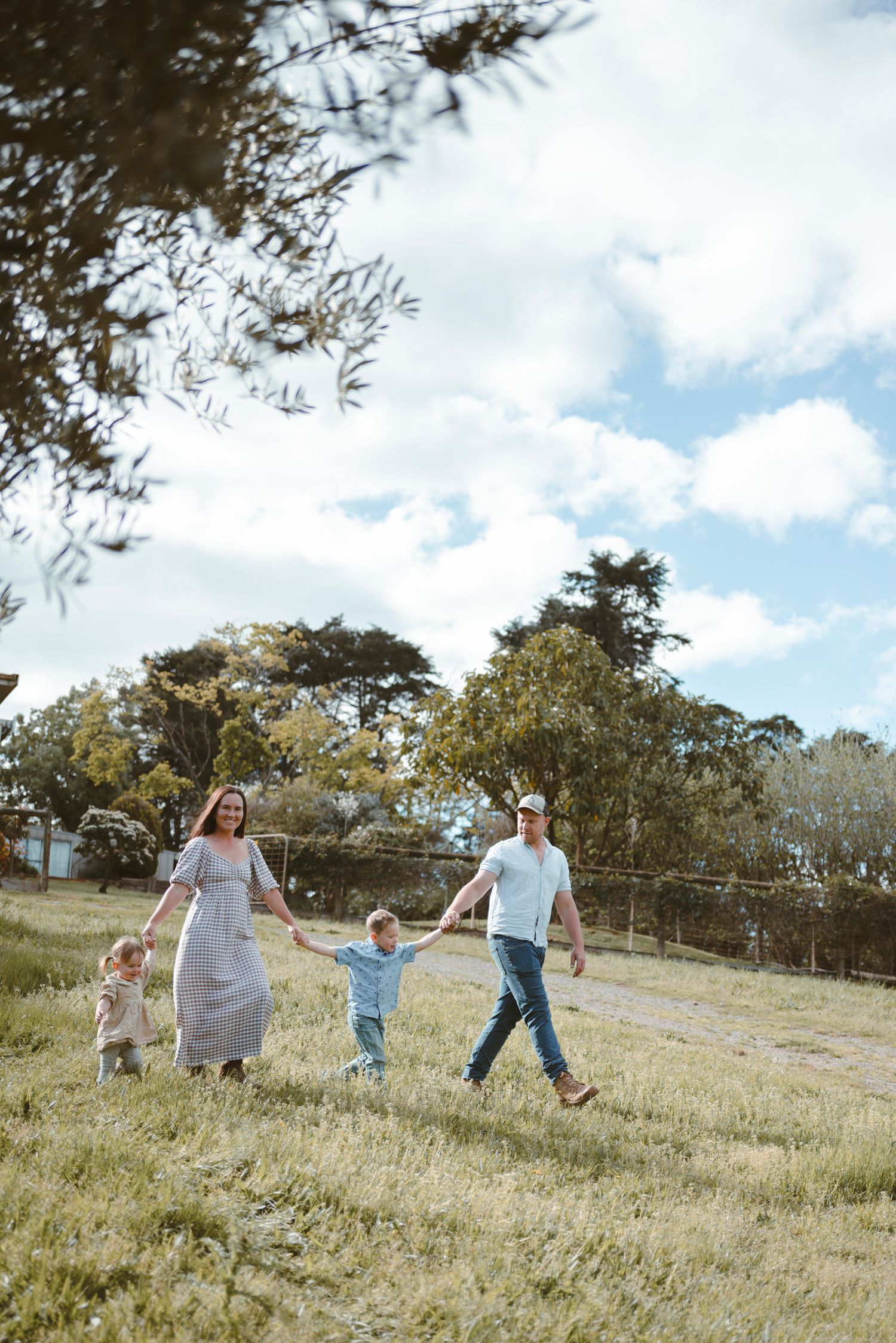 Family running and playing together in a grassy field on a bright sunny day.