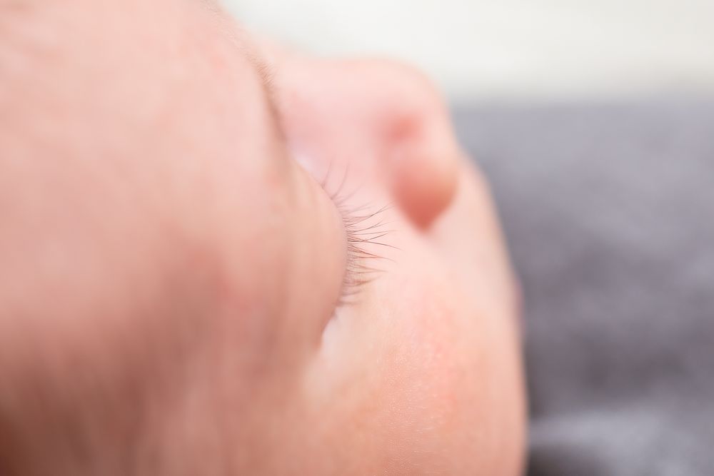 Close-up of a sleeping newborn baby's delicate eyelashes and soft skin, peaceful infant portrait.