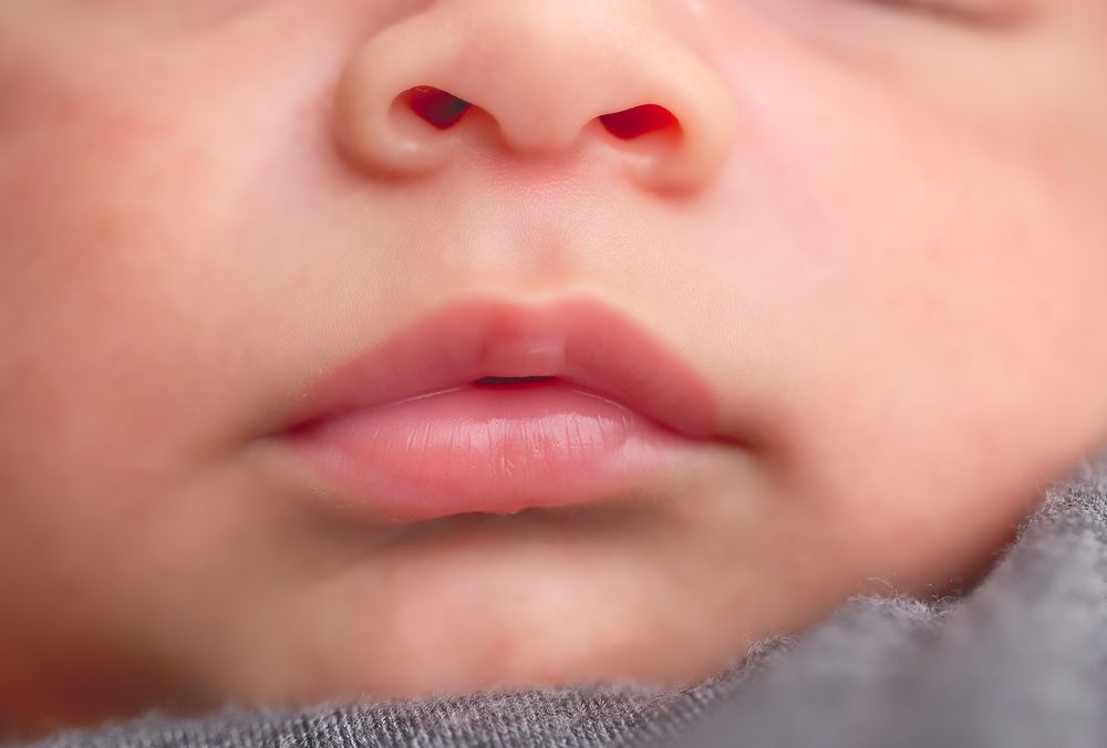 Close-up of a newborn baby's nose and lips, showing delicate skin and tiny facial features.