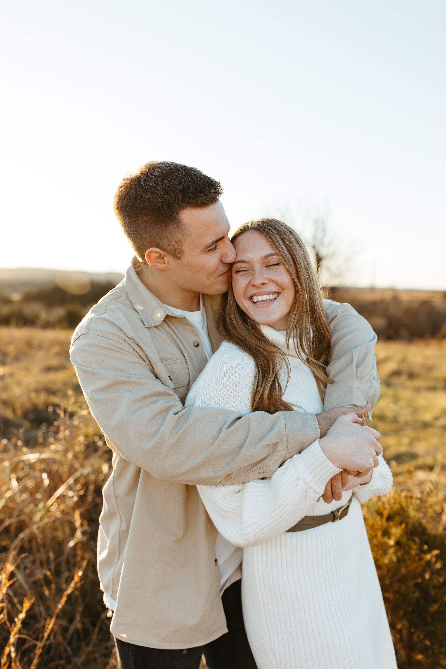 Romantic sunset moment with a couple embracing in a golden field.