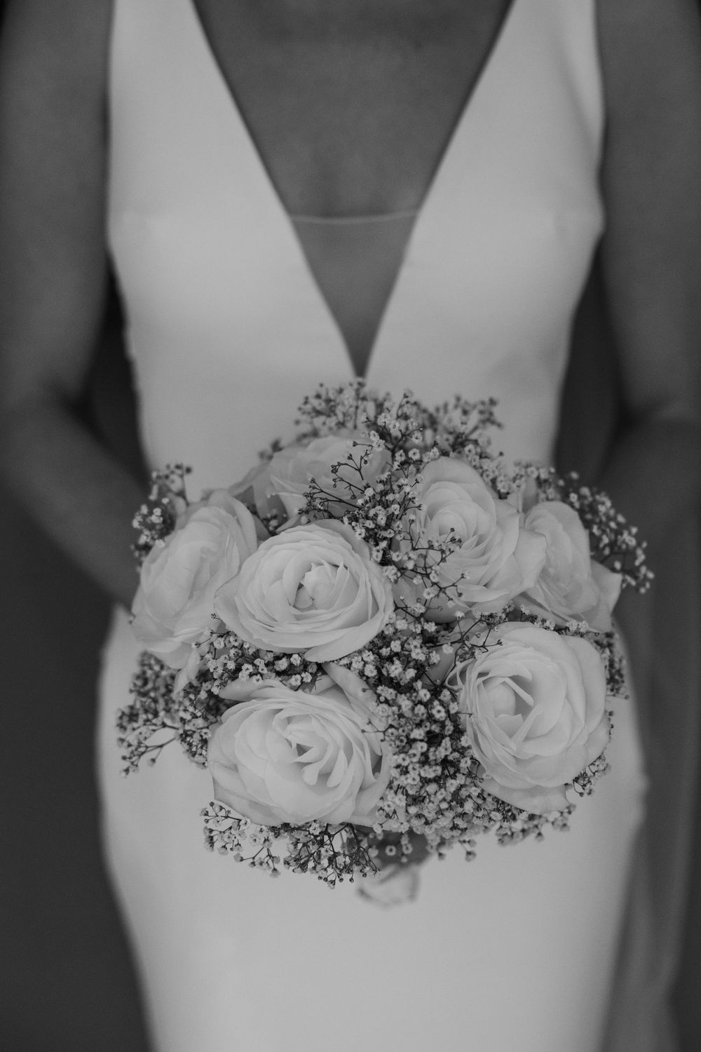 Black and white photo of a bridal bouquet with white roses and baby's breath.