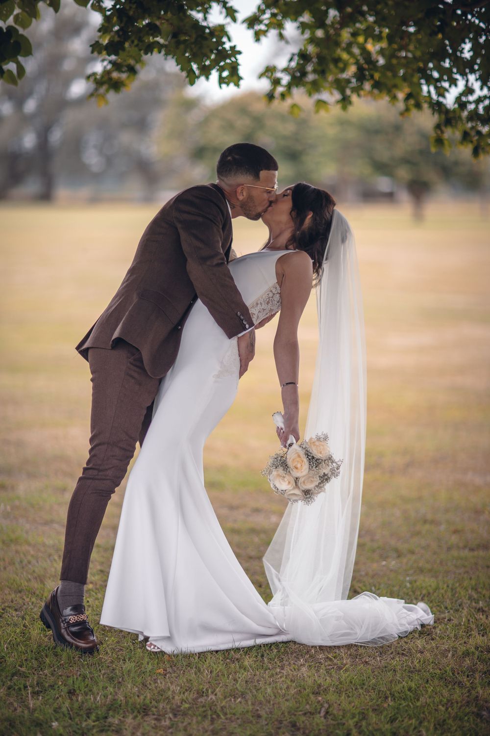Romantic wedding portrait in a field with flowing white veil.