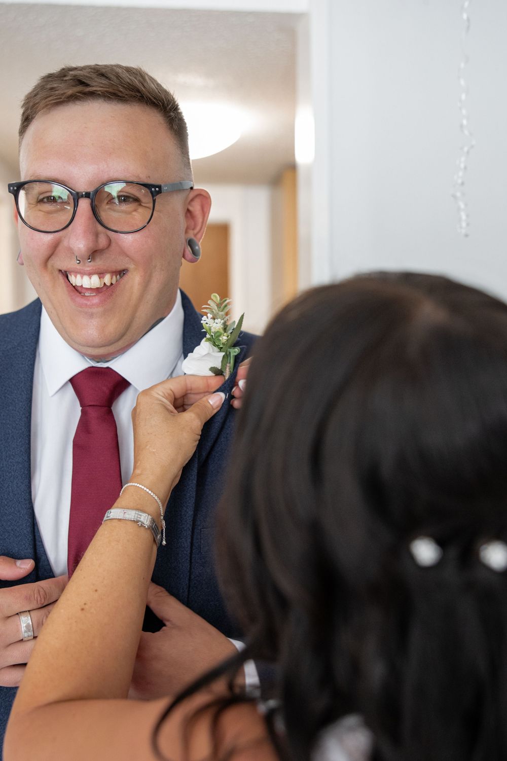 Boutonniere being pinned on groom's navy suit jacket.