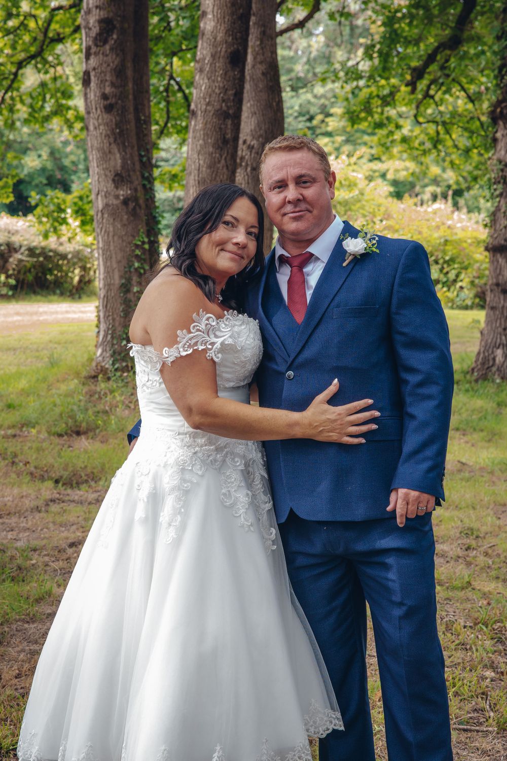 Newlyweds share intimate moment in outdoor woodland setting.