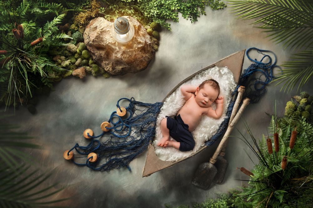 Sleeping baby in nautical setting with miniature boat and maritime decorations.