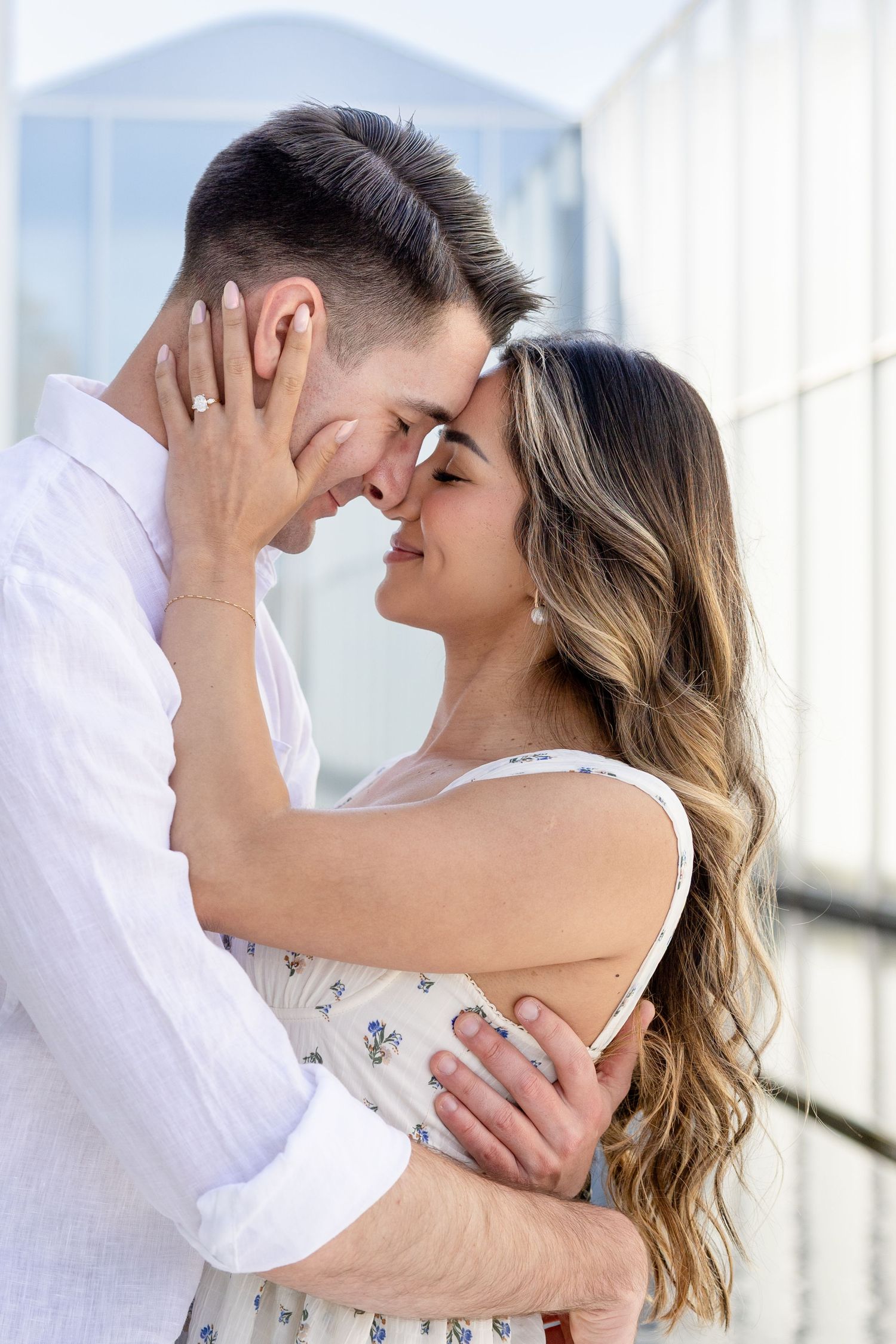 Romantic couple sharing an intimate moment together while embracing against bright white background.