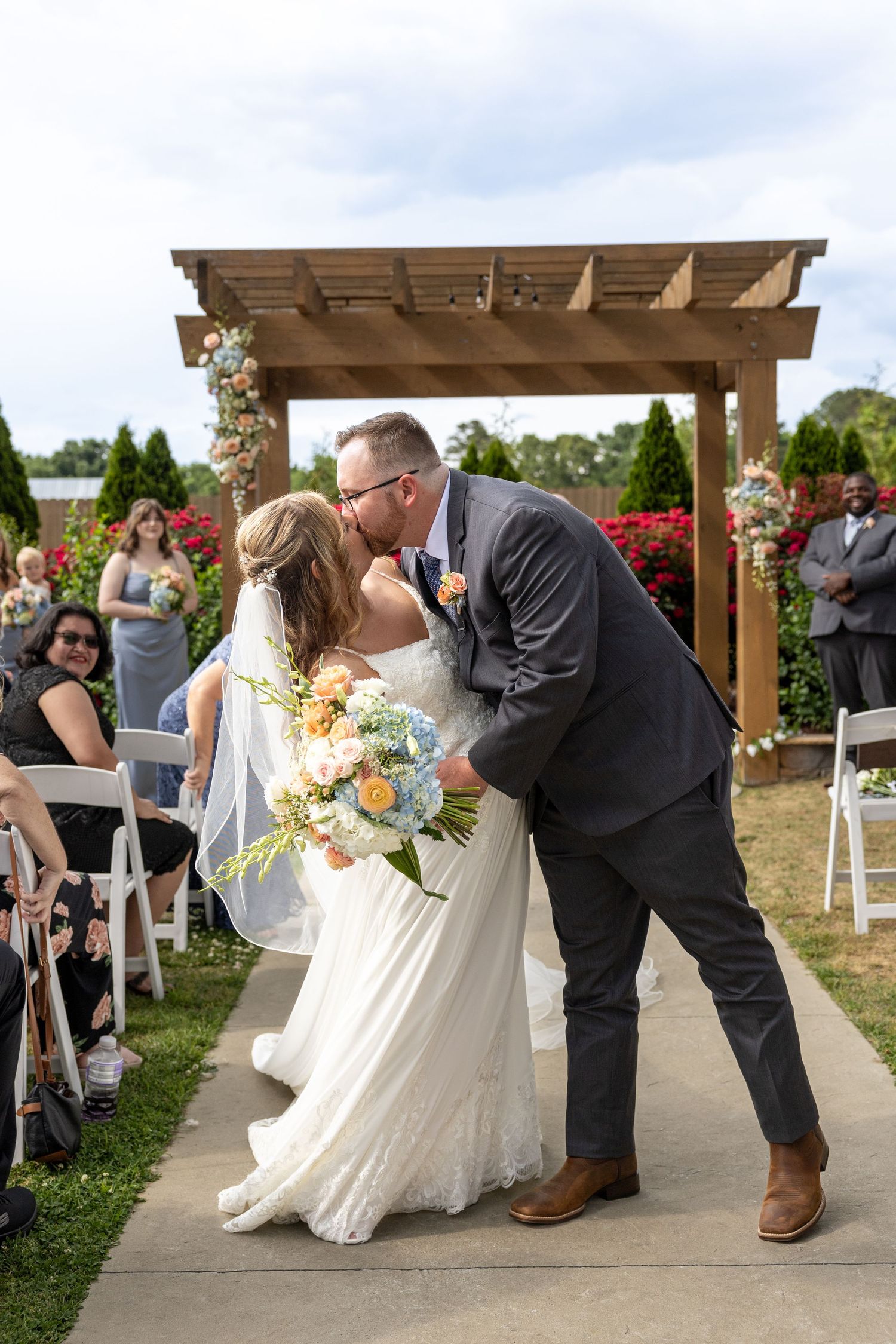 A couple kisses in the aisle after being married at Wilkins Barn in Coats, NC.