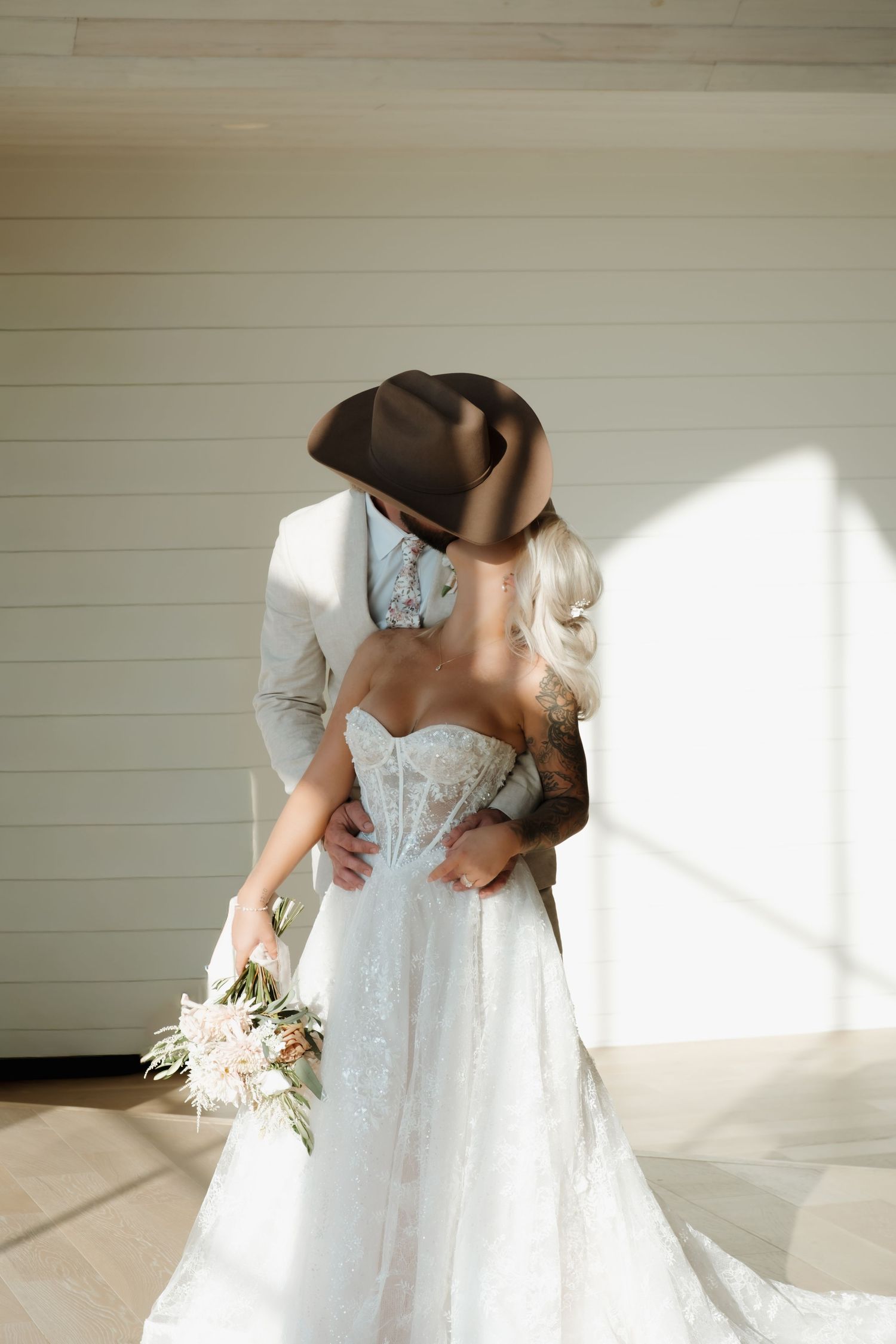 Romantic couple in wedding attire embrace on rocks near a serene pond.
