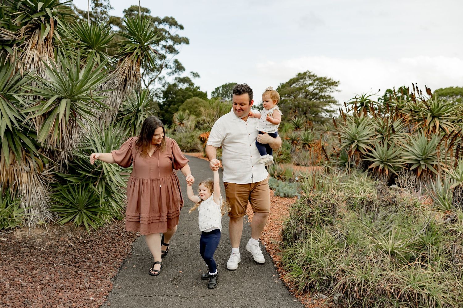 Family walking together on a dirt path during sunset with dramatic cloudy sky.