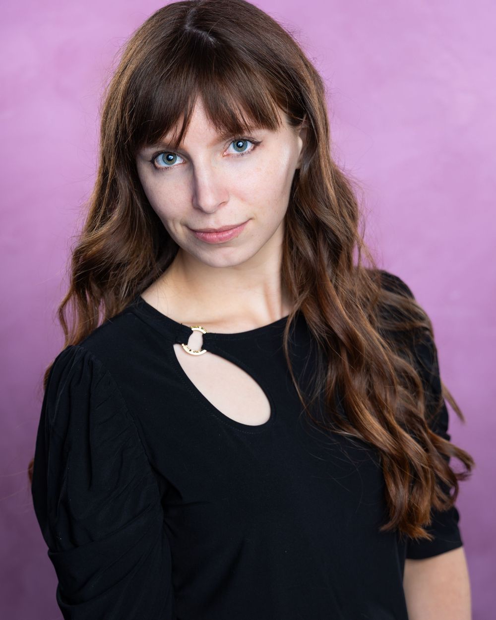 Portrait series against pink background wearing black top.