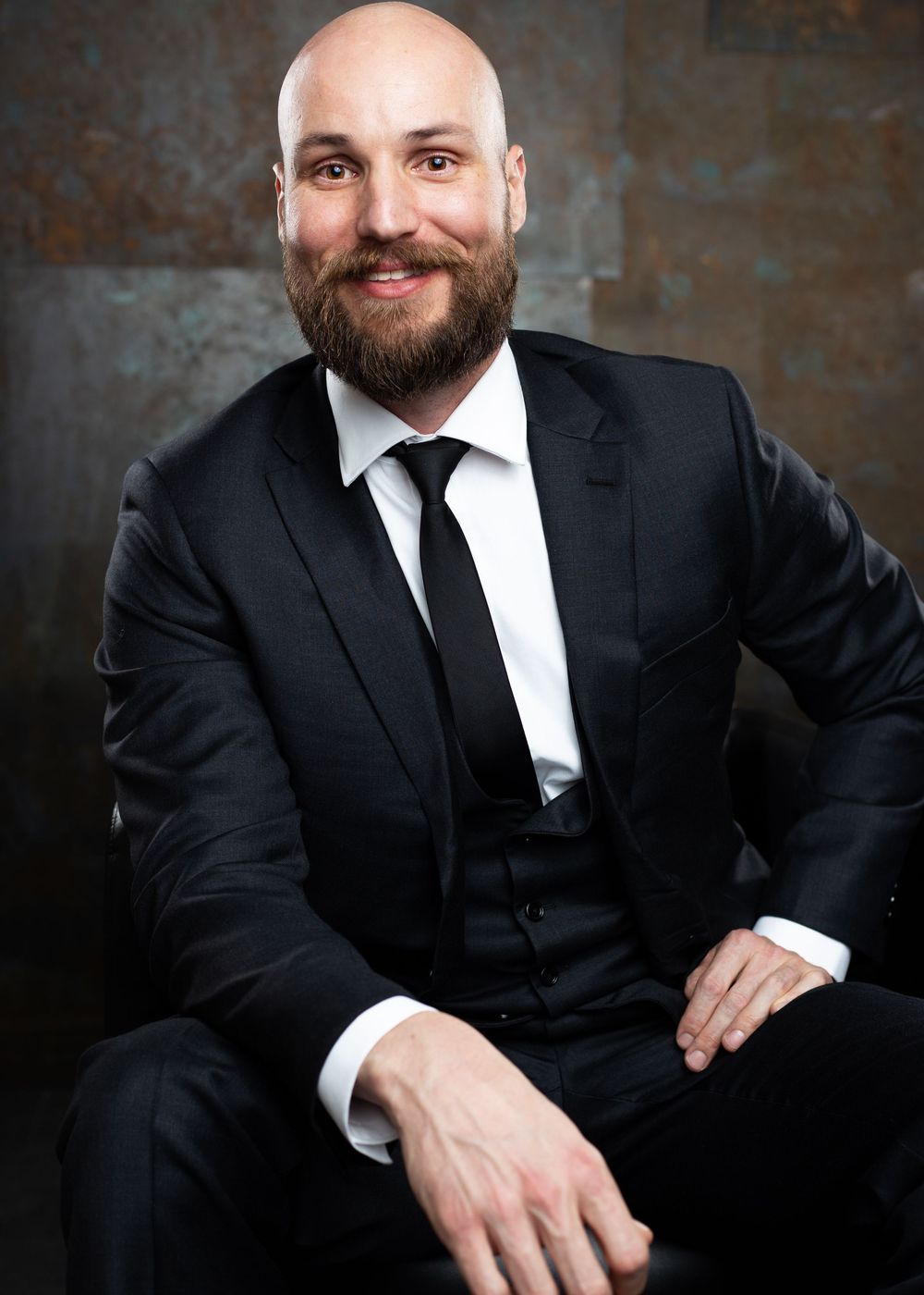 Formal portrait series showing someone in a black suit making various poses.