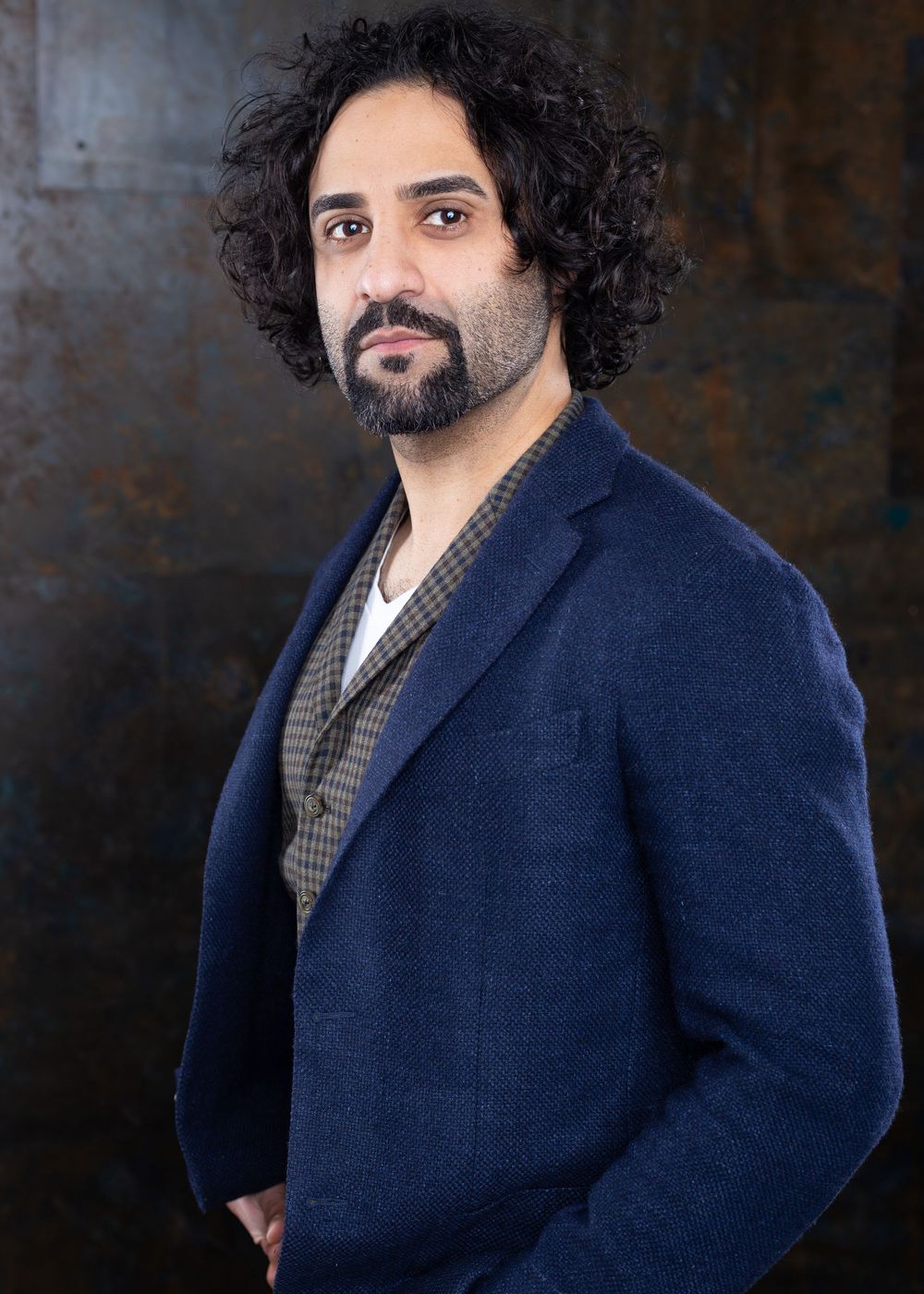 Professional portrait series showing a person with curly dark hair wearing a navy blazer against a dark background.