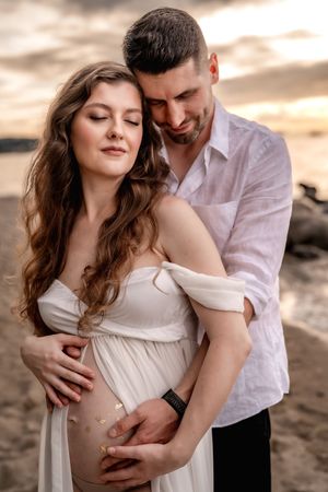 Maternity portrait in golden hour light with ocean backdrop