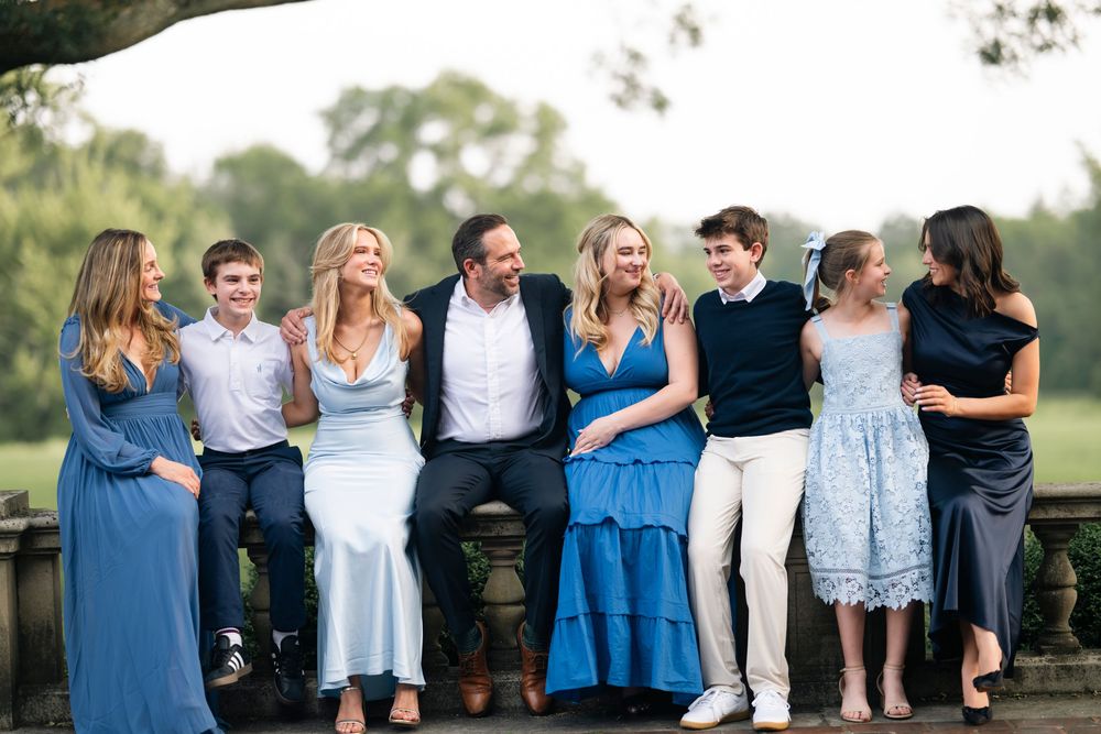 A group wearing coordinated blue and white outfits poses together outdoors for a casual photo shoot.