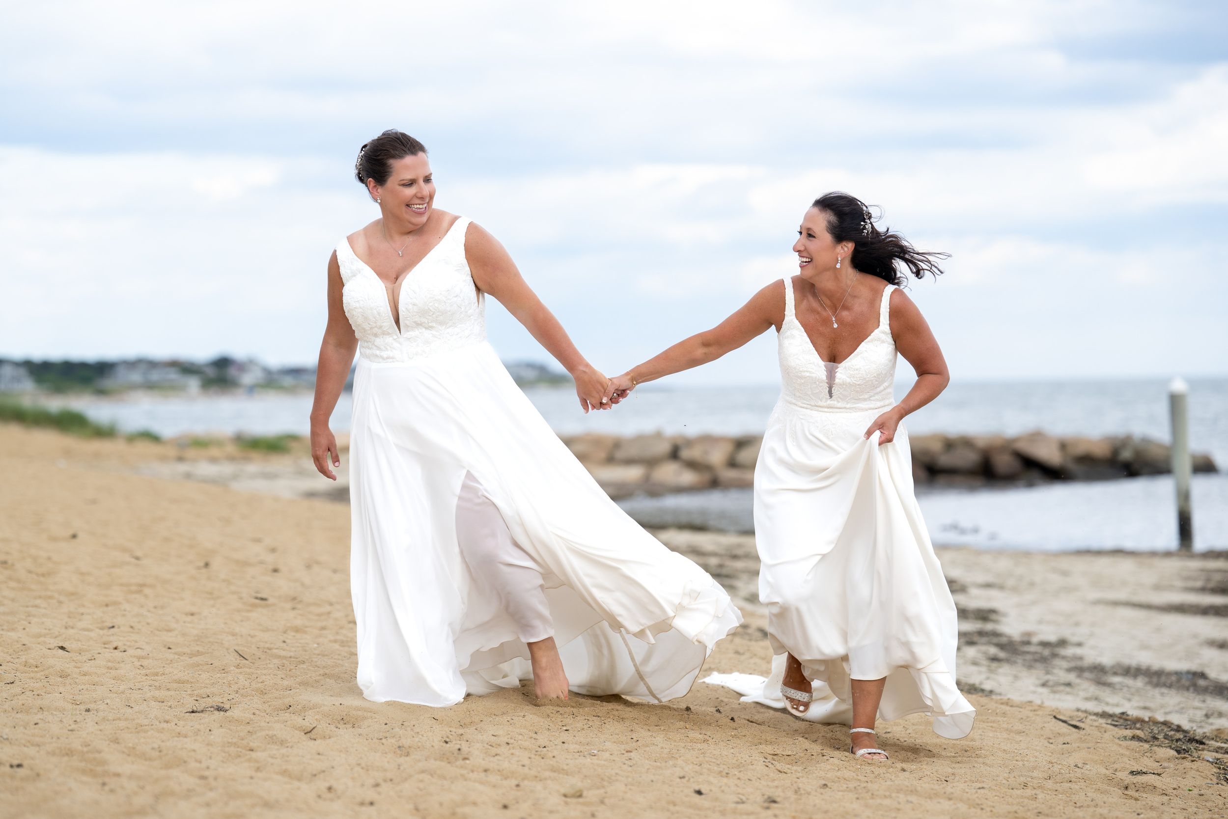 two brides running hand in hand on the beach captured by Cape Cod wedding photographer