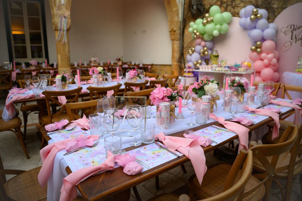 Pink-themed party table setting with balloon decorations and elegant place settings.