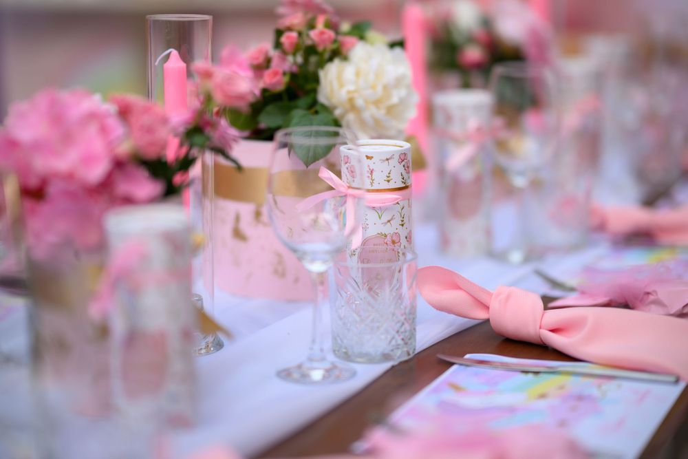 Elegant table setting with pink flowers and glassware in soft focus.