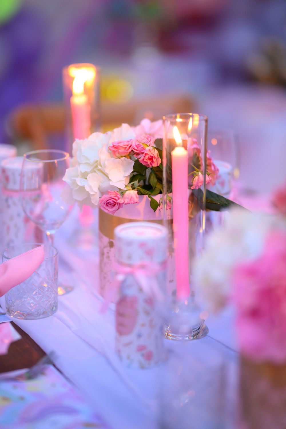 Romantic wedding table setting with pink roses and glowing candles creating an intimate atmosphere.