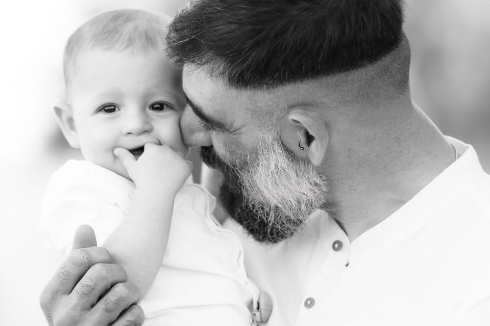 Black and white close-up portrait showing tender moment between parent and baby.