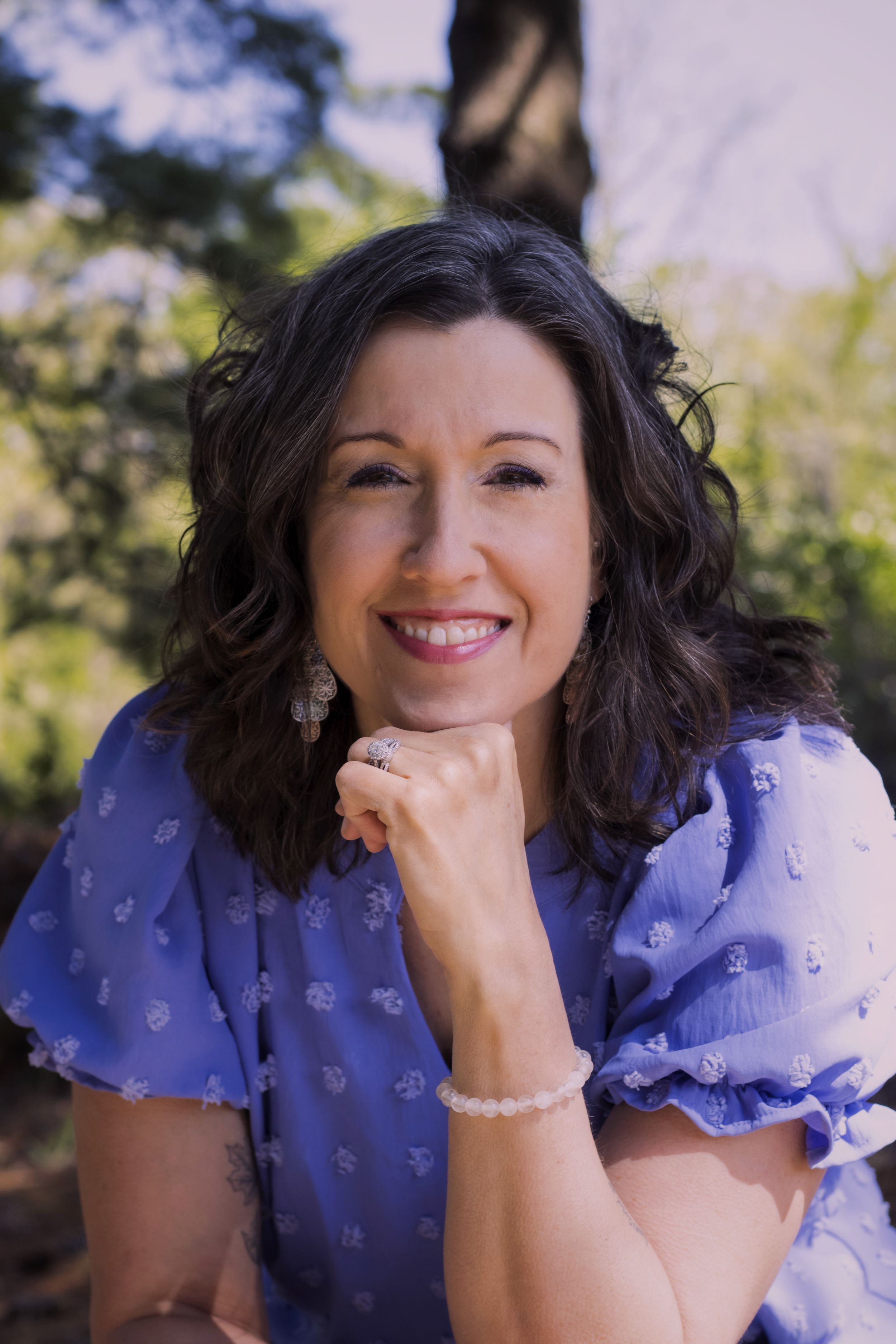 A woman smiling with trees in the background