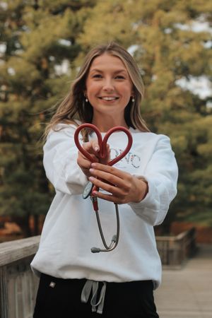 A nursing student graduate holding her stethescope for a senior photo