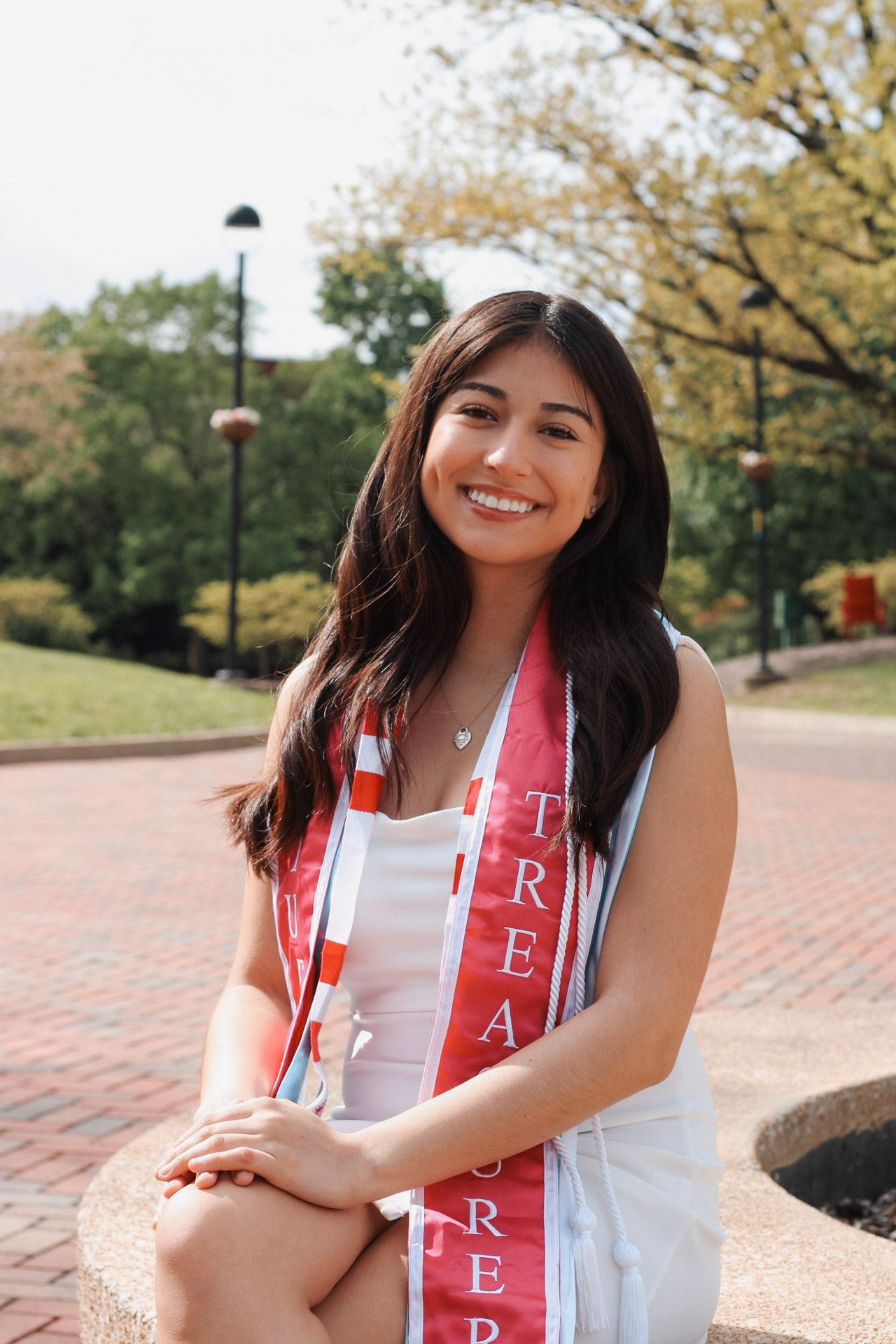 A young woman smiling on her graduation day for her senior photos outside in Edwardsville, IL