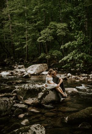 a couple sit on a big rock in the river in Western North Carolina just outside of Asheville