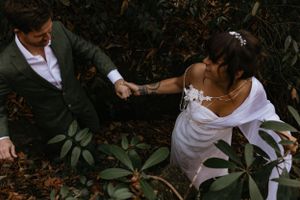 a bride leads her groom by the hand through the laurels in Western North Carolina near Asheville and Boone