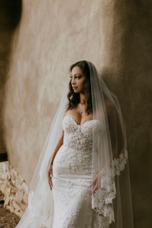 a bride leaning against a stucco wall