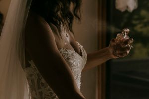 a bride sprays perfume on her chest before her wedding