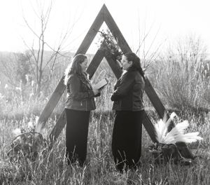 two brides stand in front of an A frame arch to share their vows in the mountains of Western North Carolina