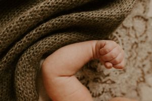 an infant appears to flex its bicep with a knit green blanket