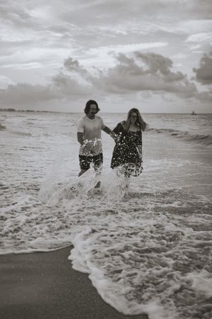 a couple runs through the surf in black and white in Anna Maria Island Florida