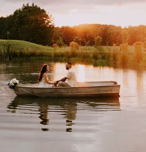 a couple float on a pond in a canoe at sunset with golden light