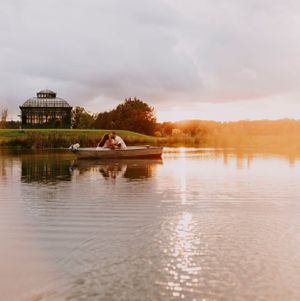 a couple float on a pond in a canoe at sunset with golden light and a solarium in the background