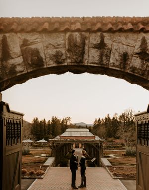 a couple framed by a stone archway overlooking the gardens at Biltmore Estate in the Blueridge mountains of Asheville North Carolina