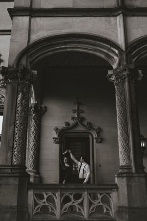 a monochrome shot of a couple dancing framed in a stone archway with immaculate architecture