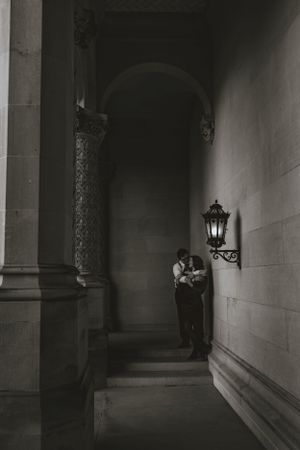 a monochrome shot of a couple in a stone corridor with a single lamp burning