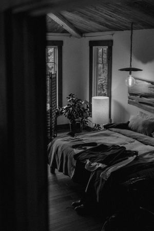 a grooms suit lays on the bed awaiting him shot in black and white inside a home