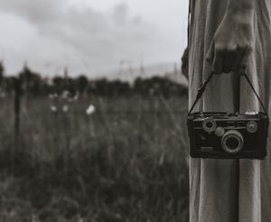 a black and white photo of a film camera in the hand of someone wearing a dress in Western North Carolina just outside of Asheville