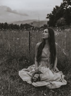a black and white photo of a young woman in a dress holding a film camera in Western North Carolina just outside of Asheville