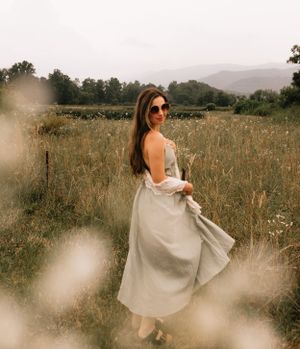 a girl in sunglasses and a dress poses in front of mountain views in Western North Carolina just outside of Asheville